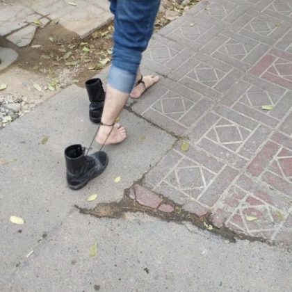 tehran university of art, A protesting student walks in the boots of his imprisoned friend, inspired by Mona Hatum, in woman, life, freedom movement